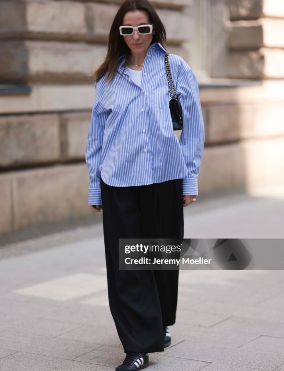  Elise Seitz seen wearing Soho Studios blue striped blouse, Hey Soho black wide pants, Zara white shades, Adidas samba black and white sneaker and a black mini Chanel handbag on May 09, 2023 in Hamburg, Germany