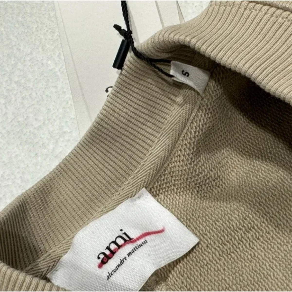 Collar label pada AMI Paris sweatshirt (Sumber foto: https://poshmark.com/)