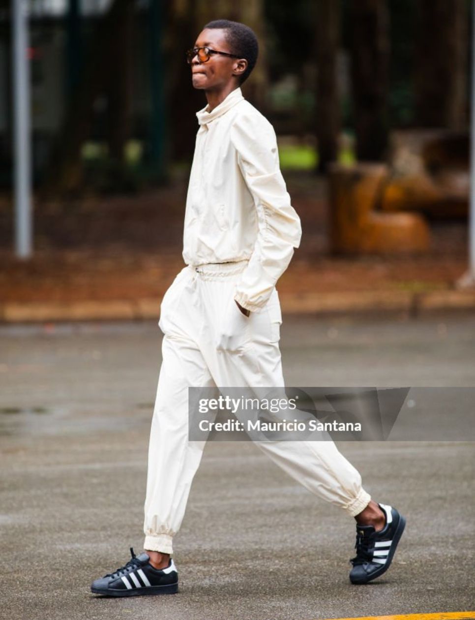 A guest wears cream tracksuit, black Adidas sneakers, brown tinted glasses at Sao Paulo Fashion Week 2024 N58 - Street Style at Parque Ibirapuera on October 20, 2024 in Sao Paulo, Brazil. (Photo by Mauricio Santana/Getty Images)