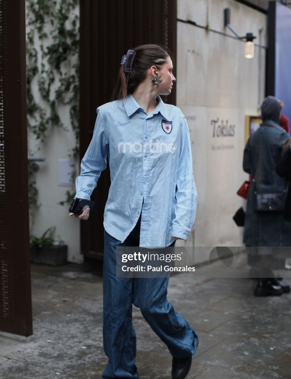 A guest is seen wearing a Martine Rose chambray shirt with a pair of jeans outside the S.S. Daley during London Fashion Week February 2025 on February 21, 2025 in London, England. (Photo by Paul Gonzales/Getty Images)