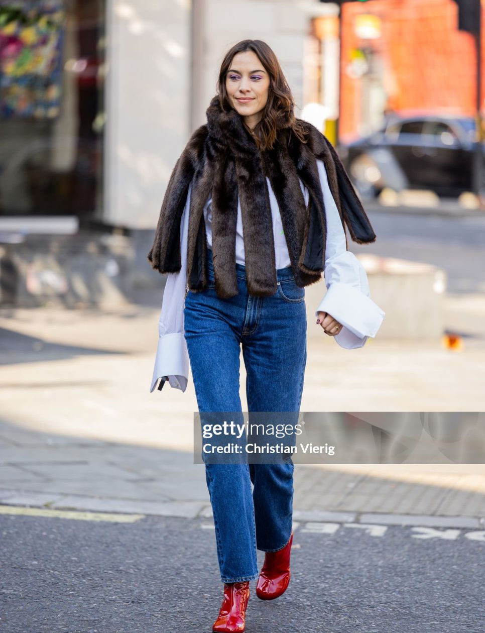 Alexa Chung wears fur cape with slits, denim jeans, white button shirt, red ankle boots outside JW Anderson during London Fashion Week September 2023 at the on September 16, 2023 in London, England. (Photo by Christian Vierig/Getty Images)