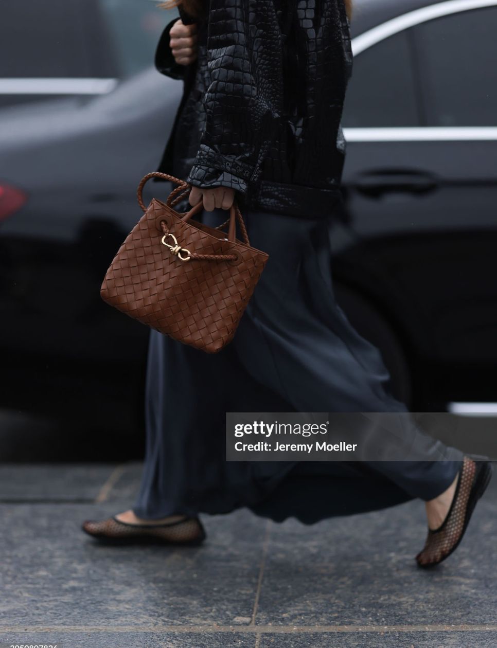 Fashion Week Guest is seen wearing black transparent sandals, a long blue skirt, a black leather jacket and a brown braided bottega veneta andiamo bag before the Off White Fashion Show during the Womenswear Fall/Winter 2024/2025 as part of Paris Fashion Week on February 29, 2024 in Paris, France. (Photo by Jeremy Moeller/Getty Images)