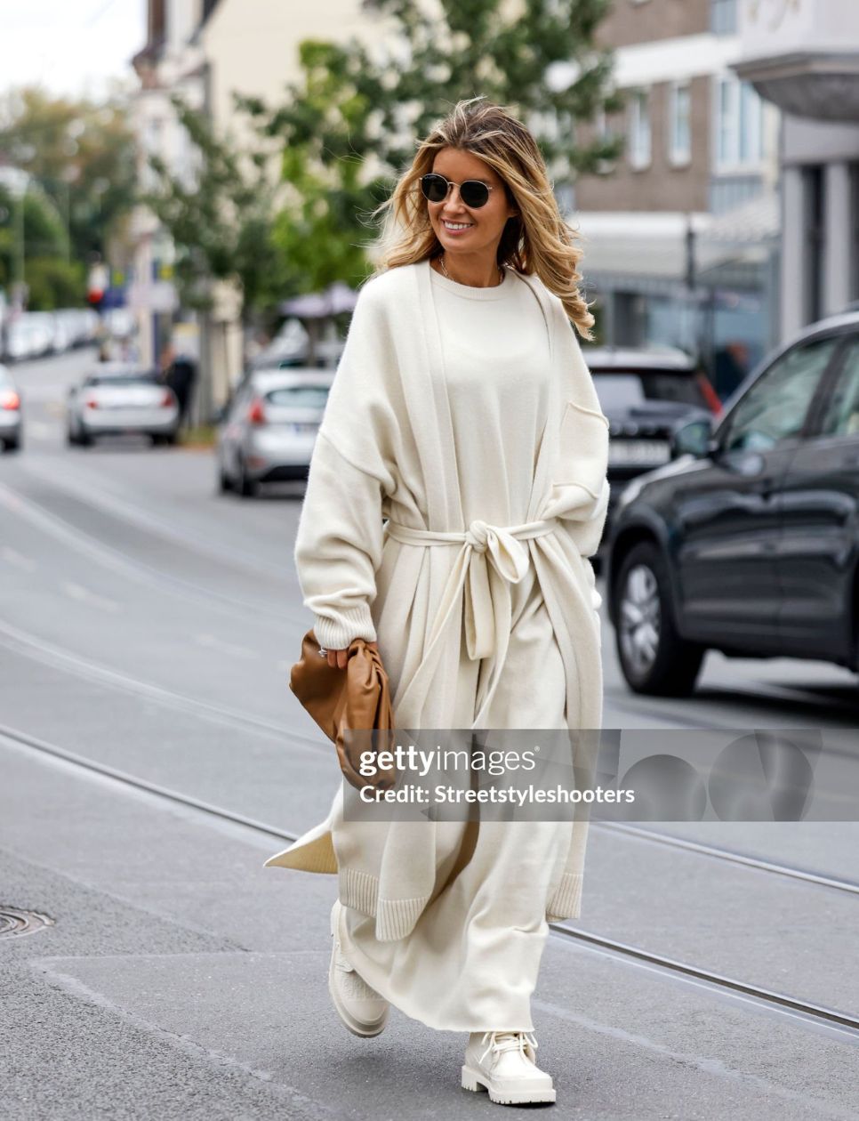 Influencer Gitta Banko wearing a monochrome cream colored look with a long cashmere cardigan by Extreme Cashmere, a oversized maxi dress by Extreme Cashmere, boots by Dior, a light brown pouch bag by Bottega Veneta and sunglasses by Ray-Ban, all by loui.rocks during a street style shooting on October 12, 2021 in Essen, Germany. (Photo by Streetstyleshooters/Getty Images)