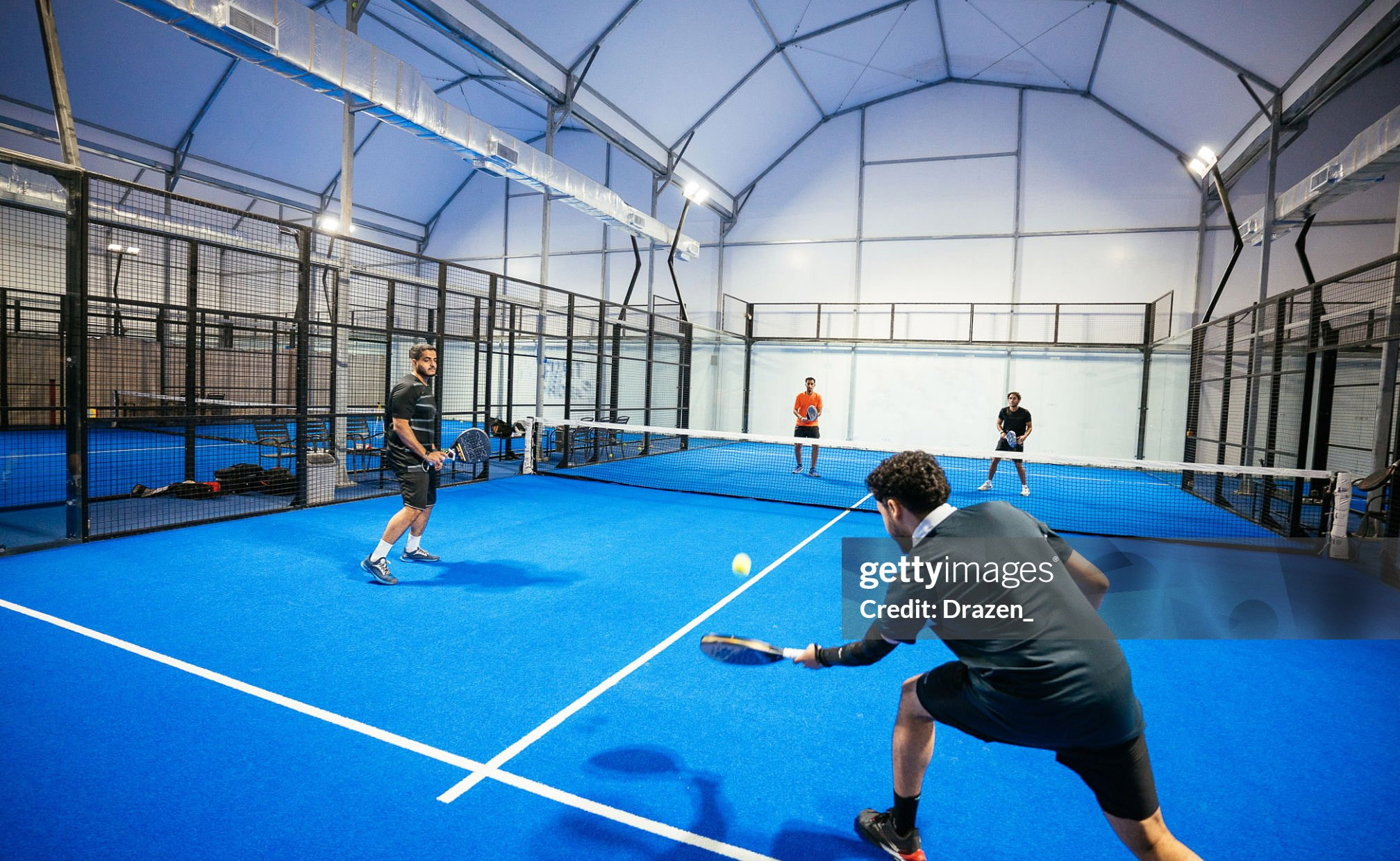 Group of skilled padel players playing padel match on new court indoors at night - stock photo Padel game Getty Images