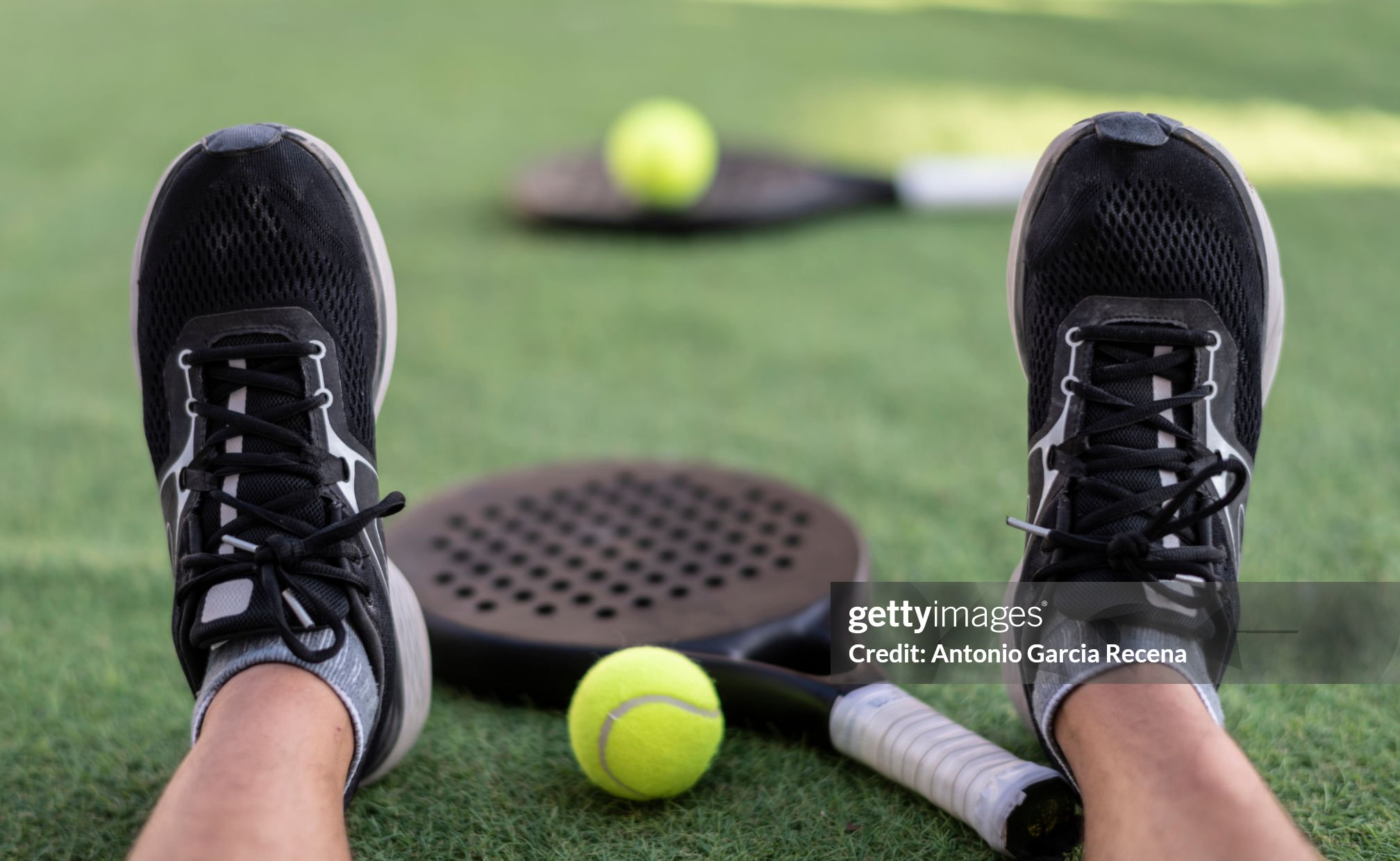 Paddle tennis rackets and ball on turf, tired players feet detail Getty Images