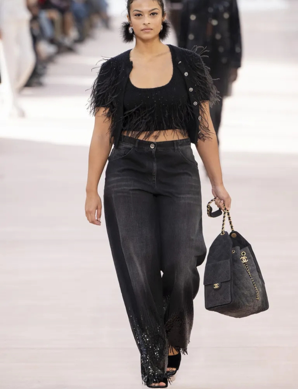 On the Spring 2025 runway, the Chanel 25 bag accompanied embellished jeans paired to feather-coated bolero sweaters (sumber gambar: https://www.marieclaire.com/fashion/chanel-25-bag/)