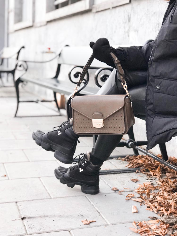 Faceless woman showing trendy hand bag while resting on bench (pexels.com)