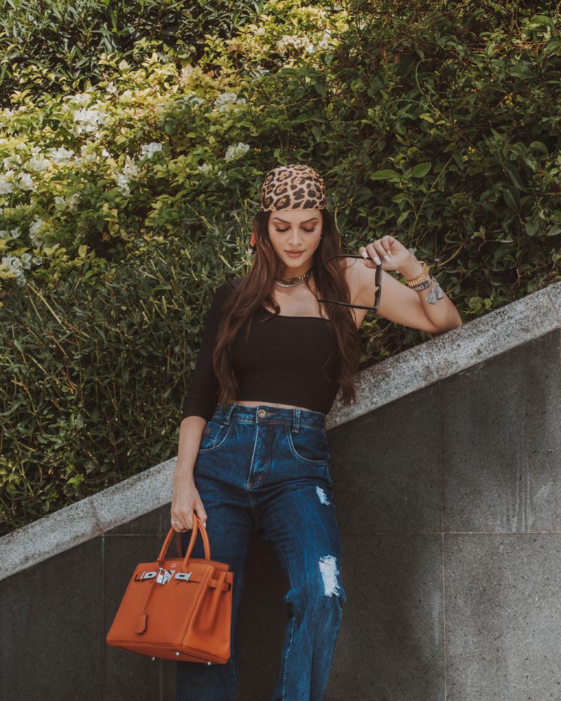 Woman in a Black Top and Denim Jeans Holding an Orange Bag (pexels.com)